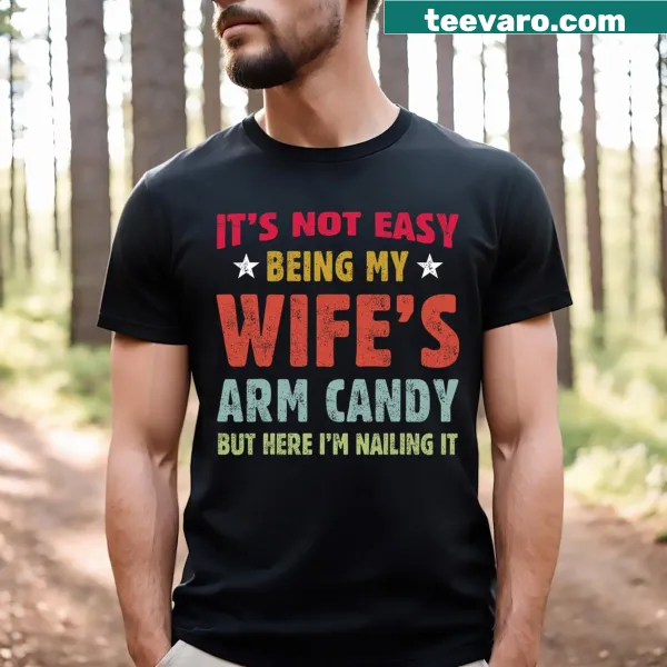 Funny T-shirt stating 'It's Not Easy Being My Wife's Arm Candy Husband'
