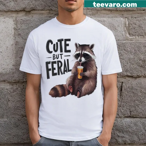 Whimsical raccoon graphic with 'Cute But Feral' text on a t-shirt