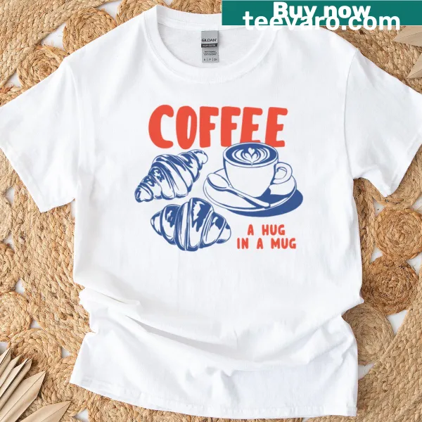 Retro t-shirt featuring coffee and croissant graphics with the phrase 'Coffee A Hug In A Mug'