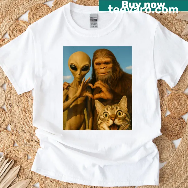 Cartoon T-shirt featuring a cat taking a selfie with Bigfoot and an alien