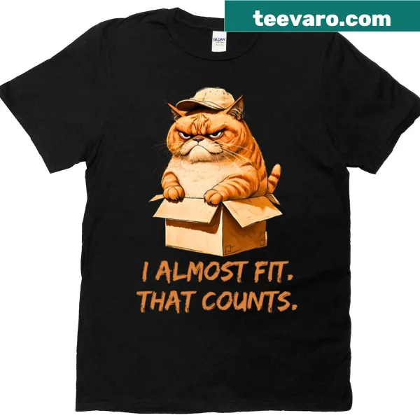 Cartoon cat in a box wearing a cap with 'I Almost Fit' text
