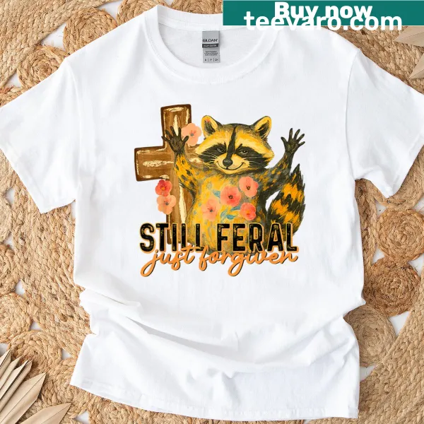 Vintage T-shirt with a raccoon and a Christian cross design, captioned 'Still Feral Just Forgiven'