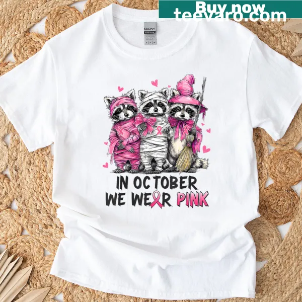 Whimsical raccoon illustration on a pink Halloween awareness tee