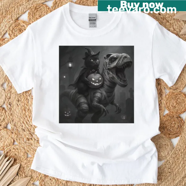 Cute T-shirt featuring a cat witch riding a T-rex for Halloween.