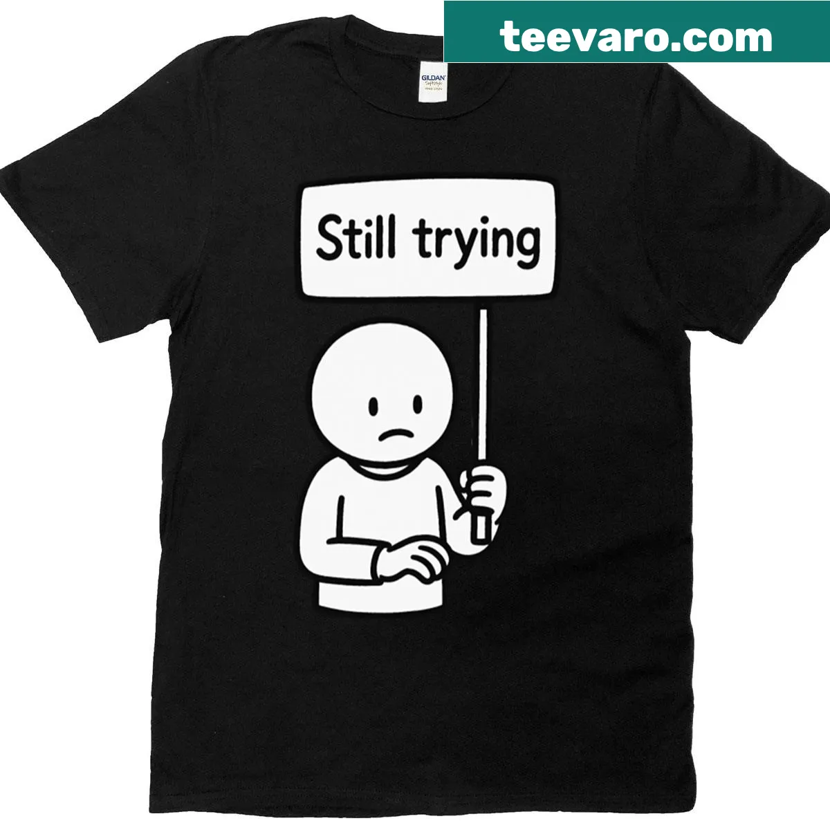 Sad cartoon character t-shirt with 'Still Trying' sign — on a men's t-shirt