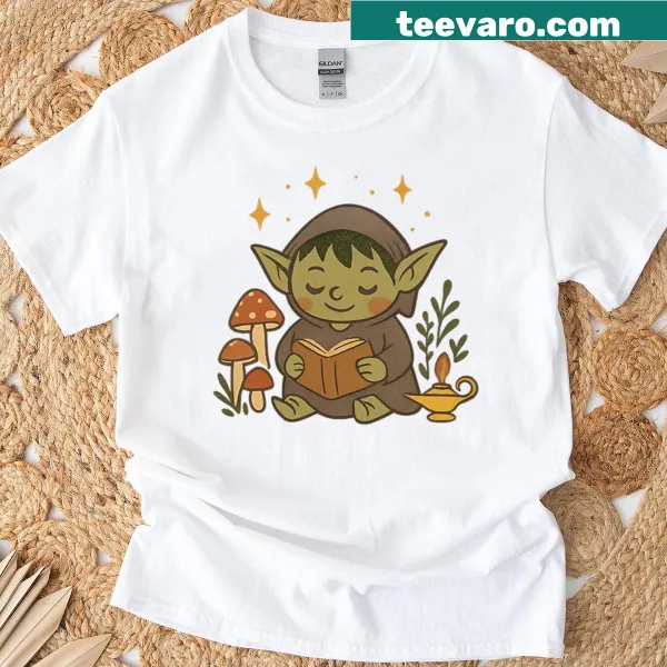 T-shirt featuring a cozy goblin reading a book with cottagecore vibes