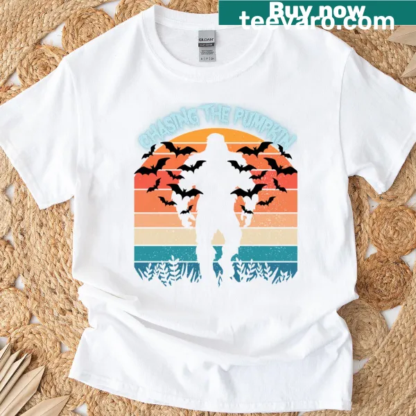 Funny T-shirt featuring Sasquatch chasing a pumpkin at sunset